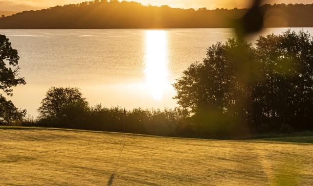 view of a golf course at sun set over looking the water