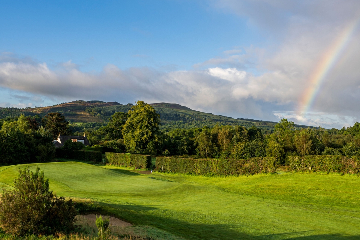 a golf course on a sunny day with a rainbow in the back ground