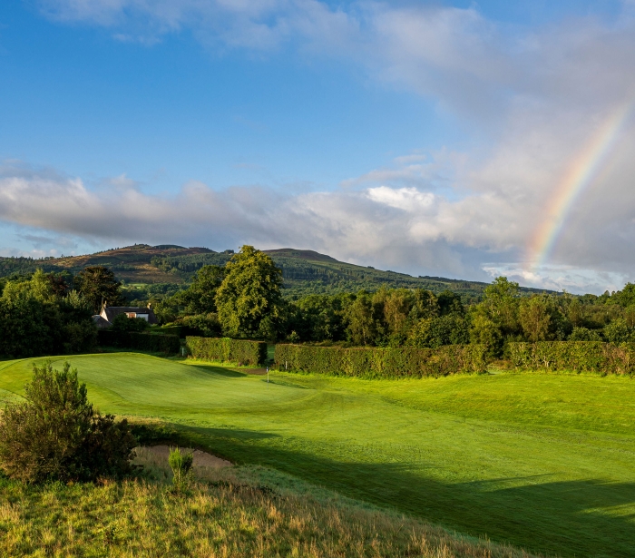 a golf course on a sunny day with a rainbow in the back ground