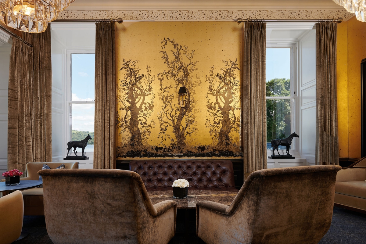 table side view of trees pained onto a wall and large windows looking into the exterior and small horse statues