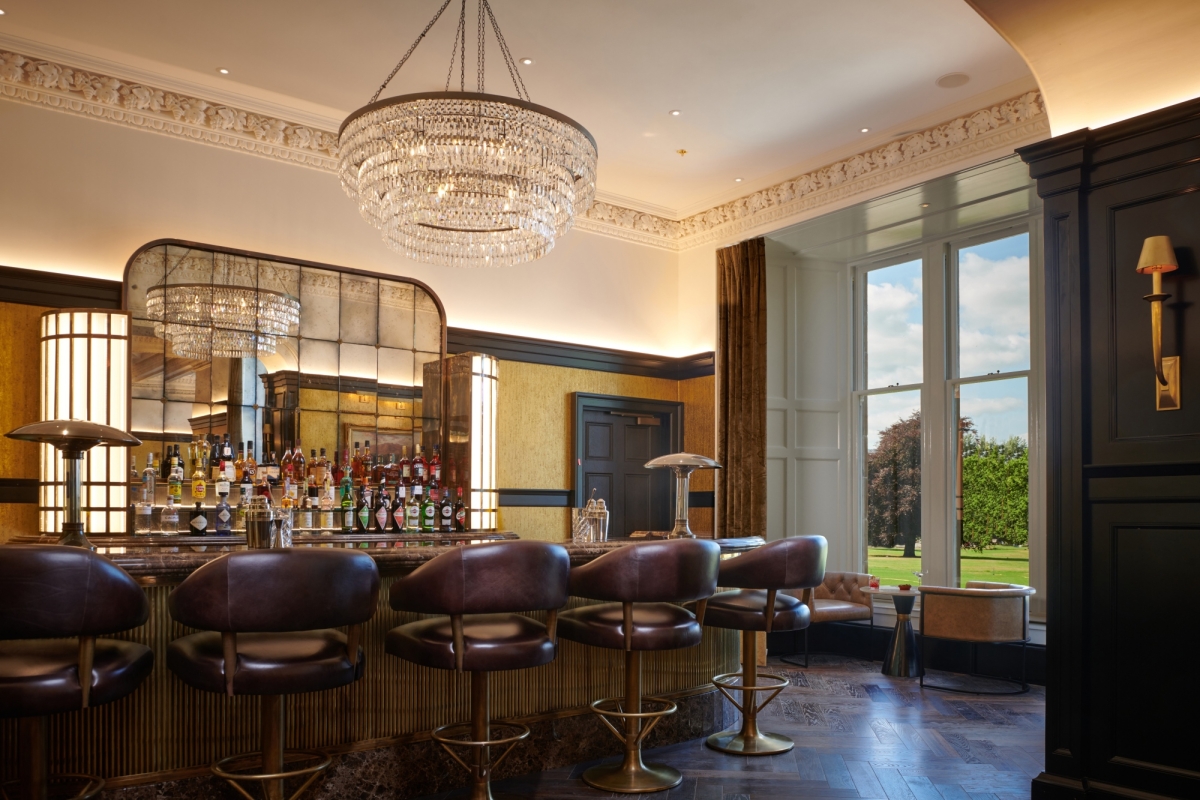 a bar with seating next to a window showing the bright green outside views