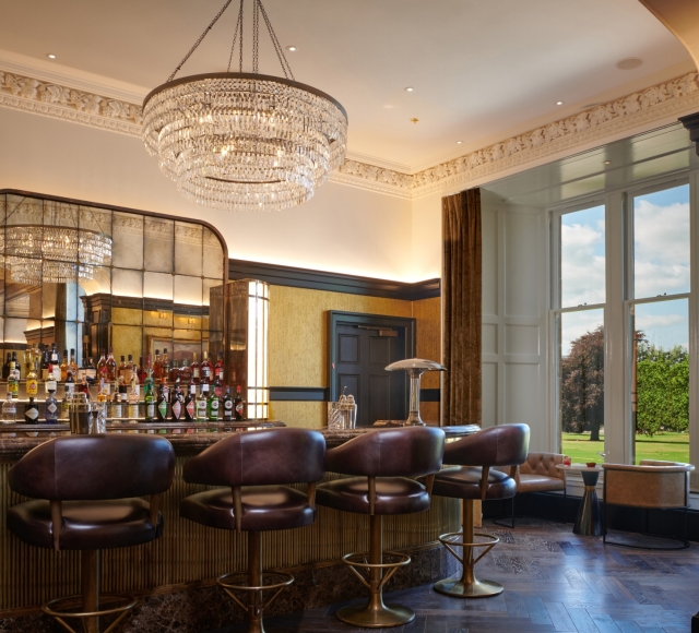 a bar with seating next to a window showing the bright green outside views