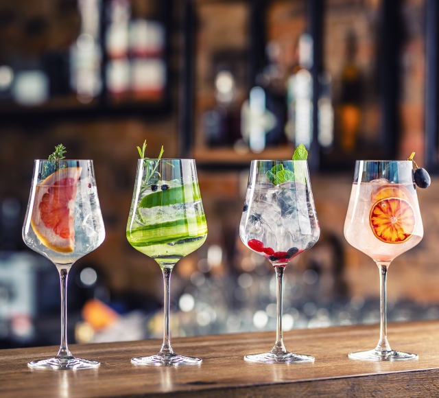 a line up of four cocktails on the counter top of the bar