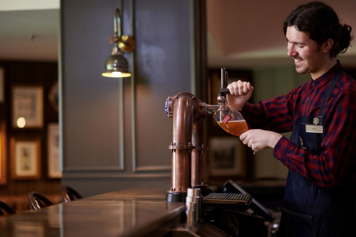 a bartender pouring a glass of beer fresh out of the tap