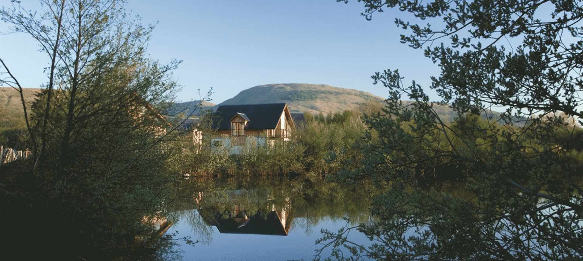 houses sitting behind a small body of water with mountains in the background