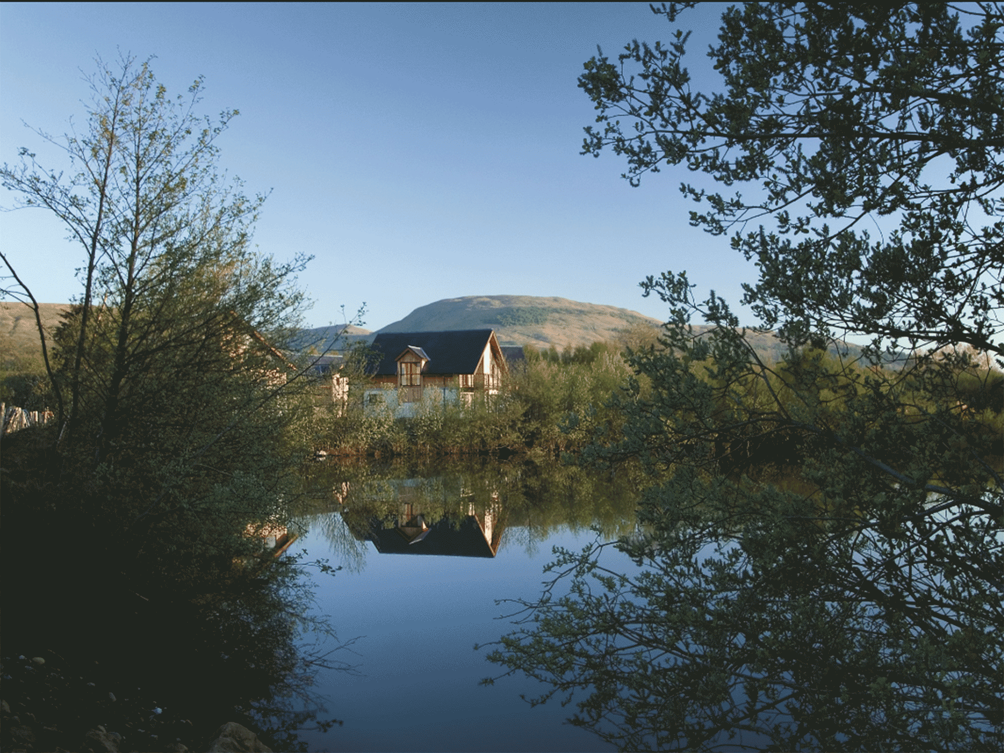 houses sitting behind a small body of water with mountains in the background