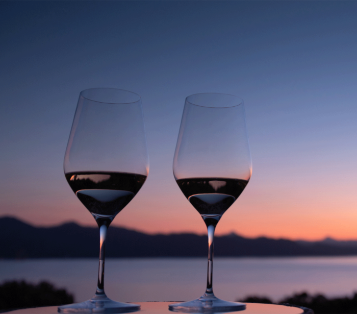 two glasses sitting on a table with the sun setting in the back ground