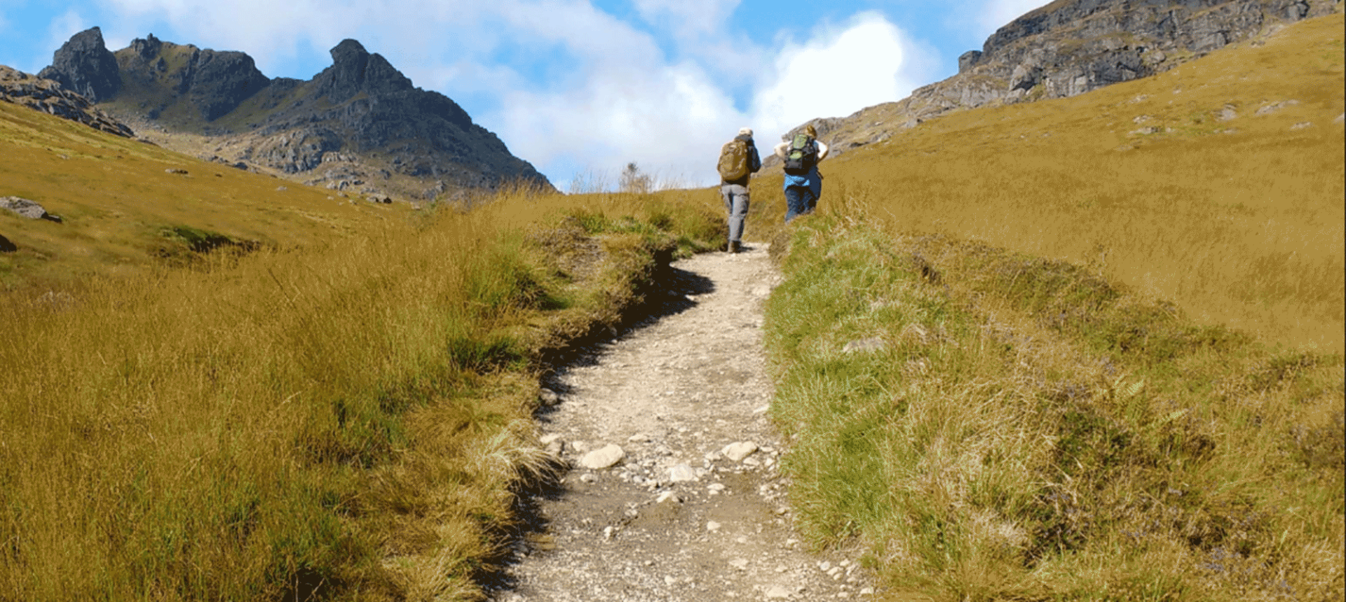 two people walking up a trail going up the side of a hill