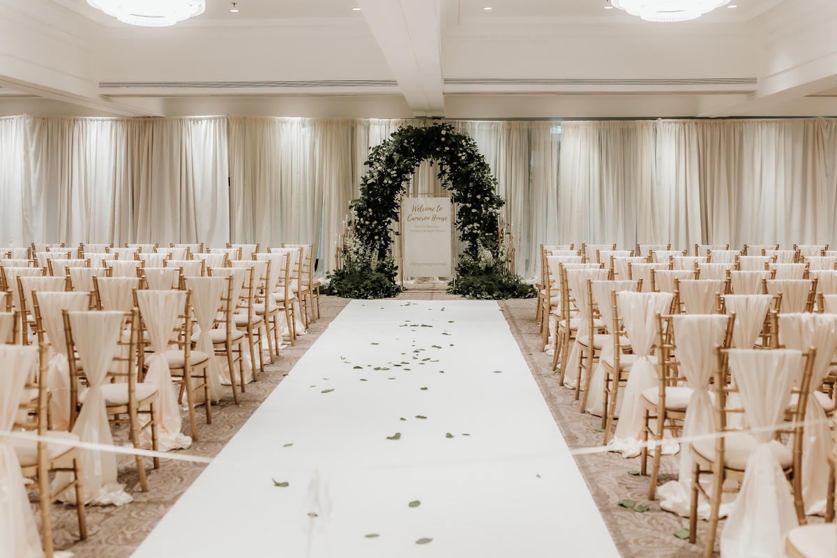 large wedding area with flower arch and white carpet leading up to it