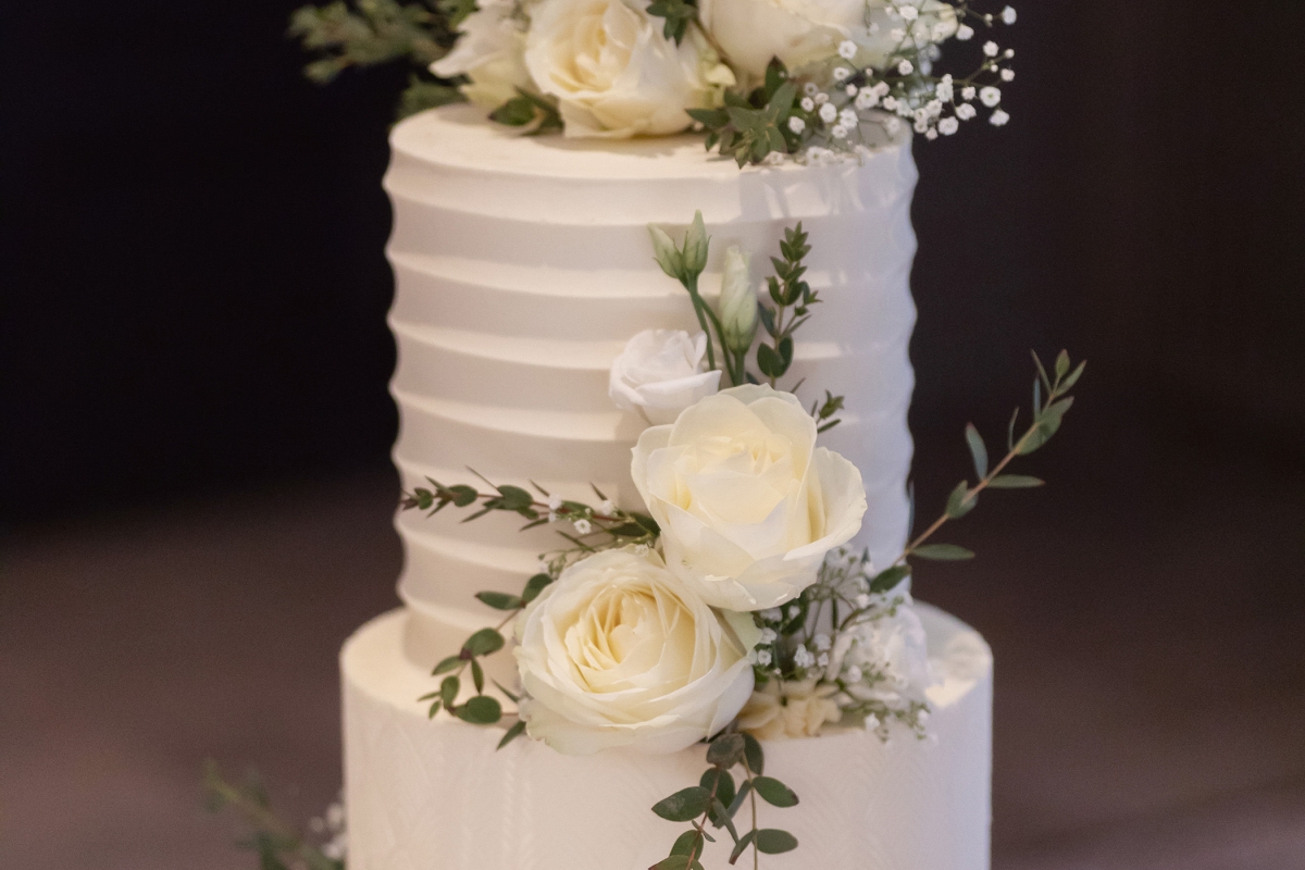 a beautiful white wedding cake with flowers on top sitting on a piece of wood