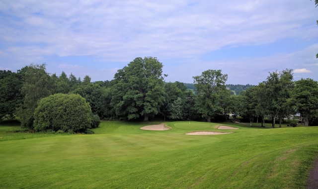 golf course with sand dunes around the hole on a cloudy day