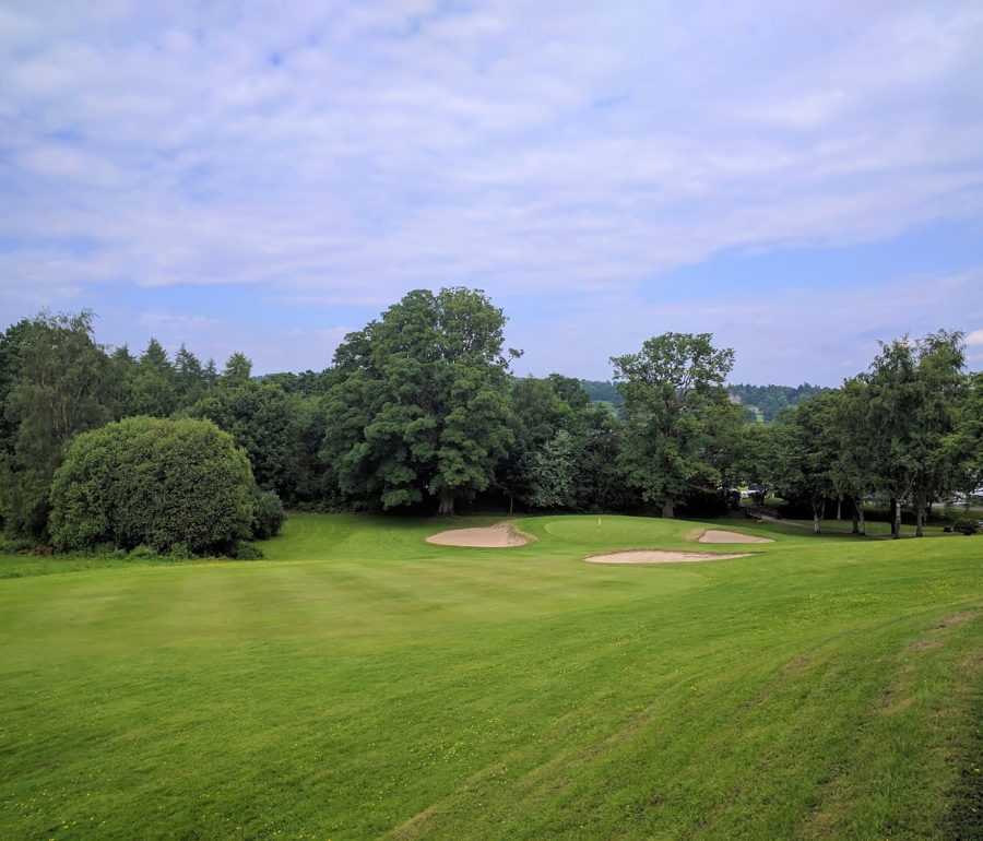 golf course with sand dunes around the hole on a cloudy day