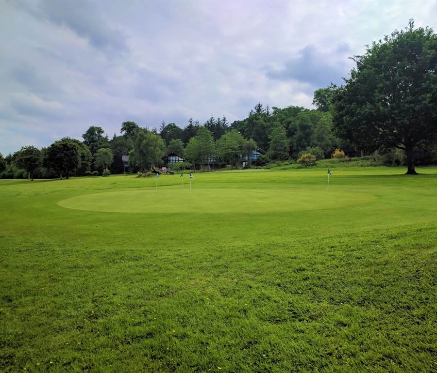 golf green with multiple holes and a building in the background