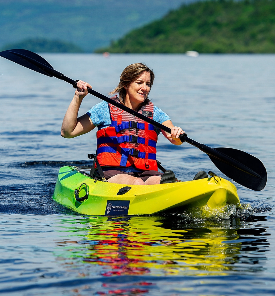 a woman riding on a yellow and green canoe on a body of water on a sunny day