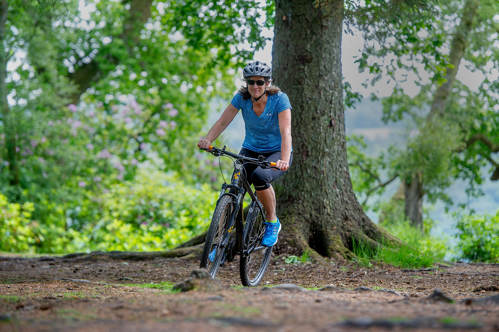 a woman riding her bike in the forest with a tree in the background