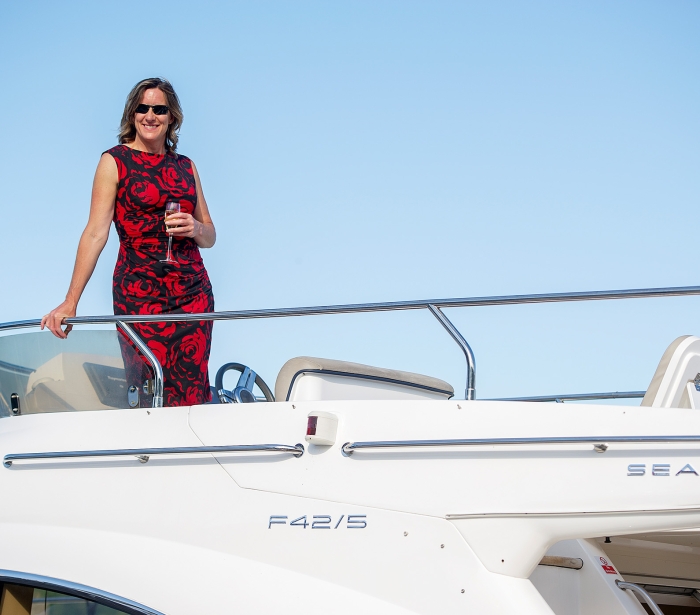 a woman standing on the top level of a boat wearing a elegant floral dress