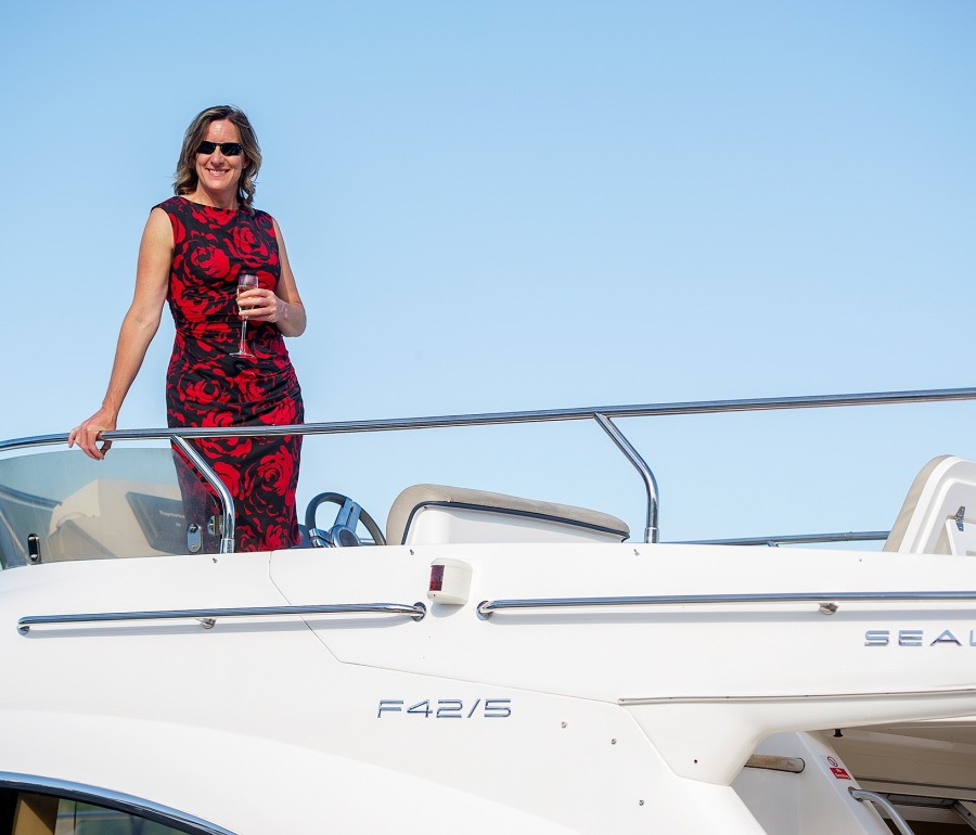 a woman standing on the top level of a boat wearing a elegant floral dress