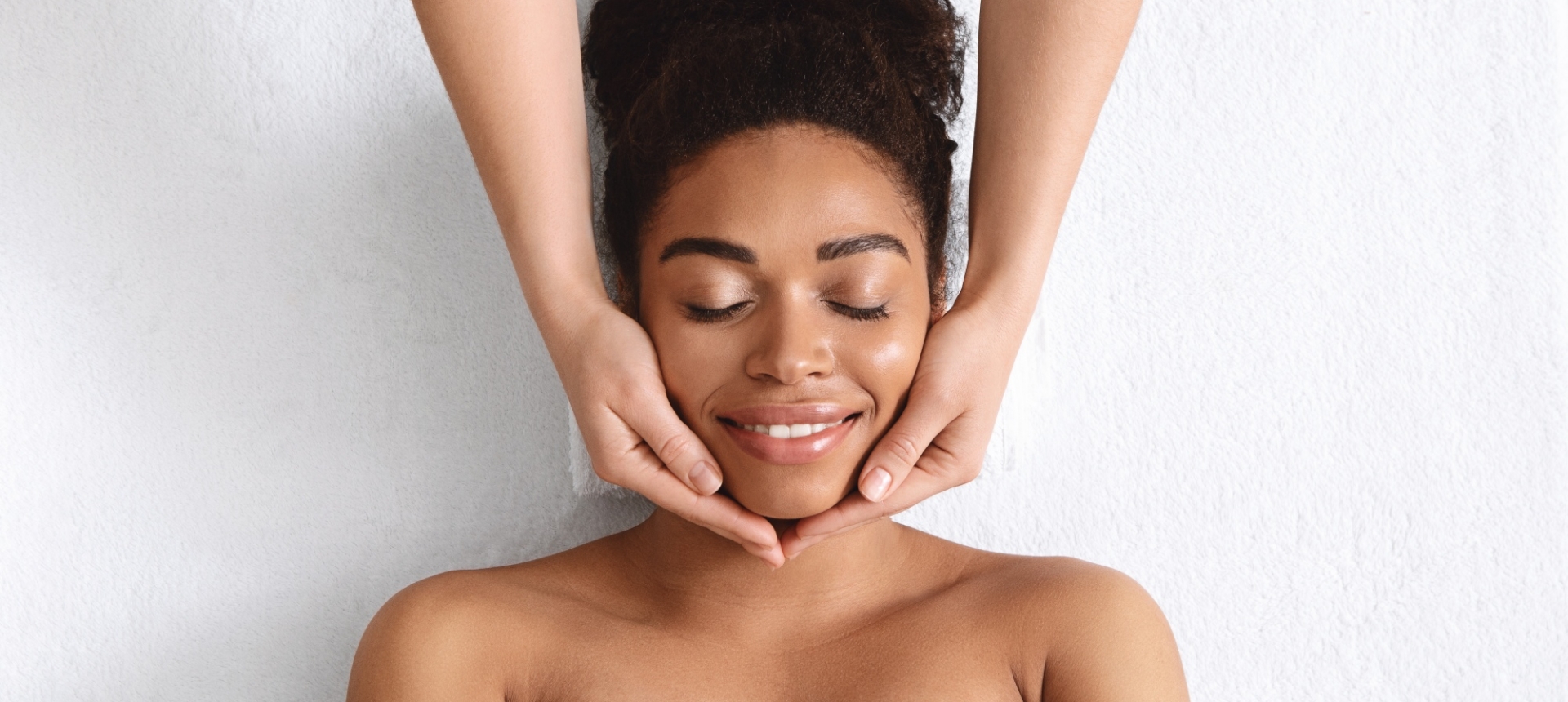 a woman laying on a table under a towel getting her face massaged