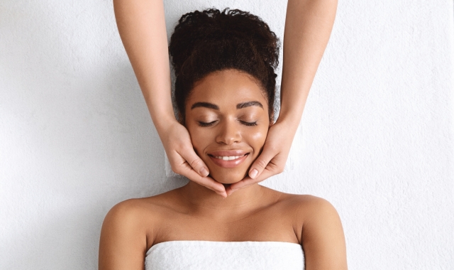 a woman laying on a table under a towel getting her face massaged