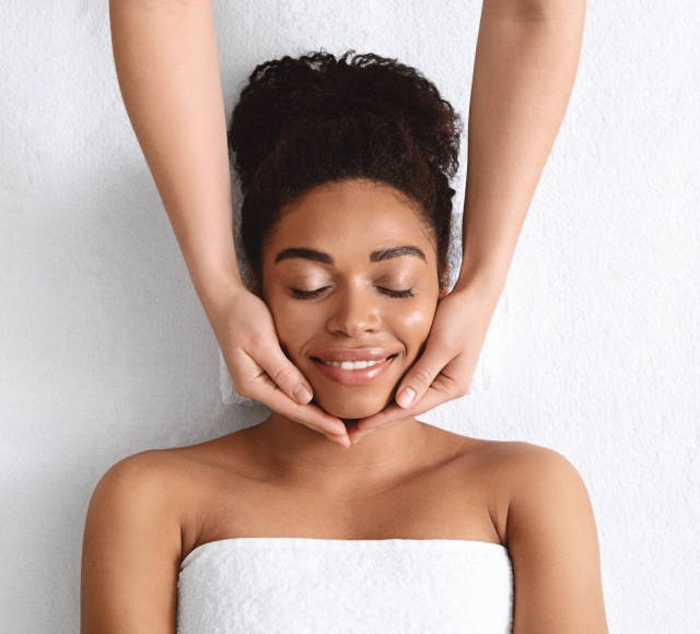 a woman laying on a table under a towel getting her face massaged