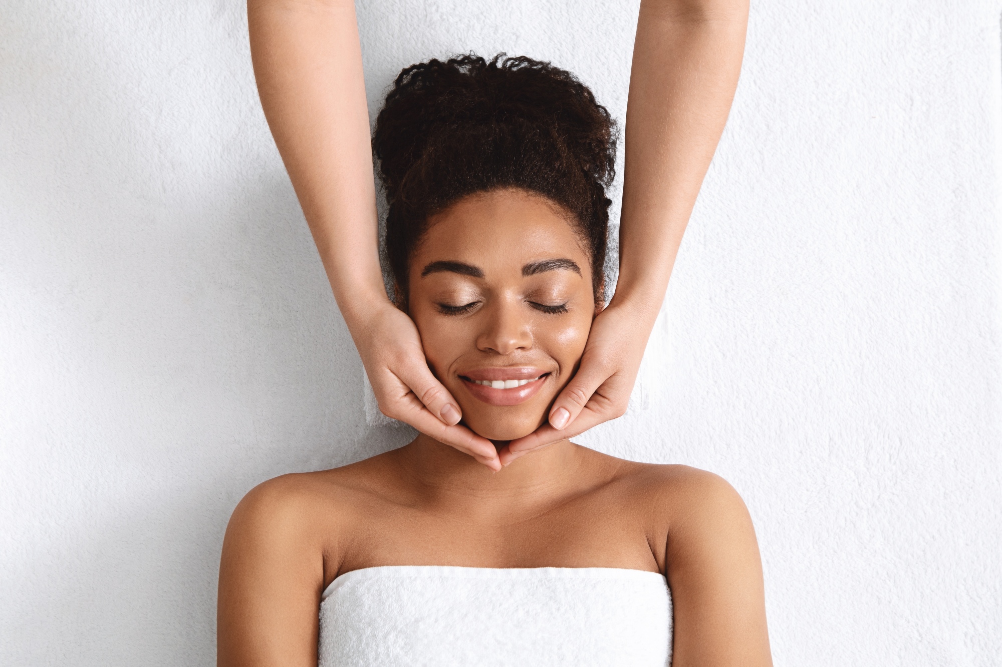 a woman laying on a table under a towel getting her face massaged