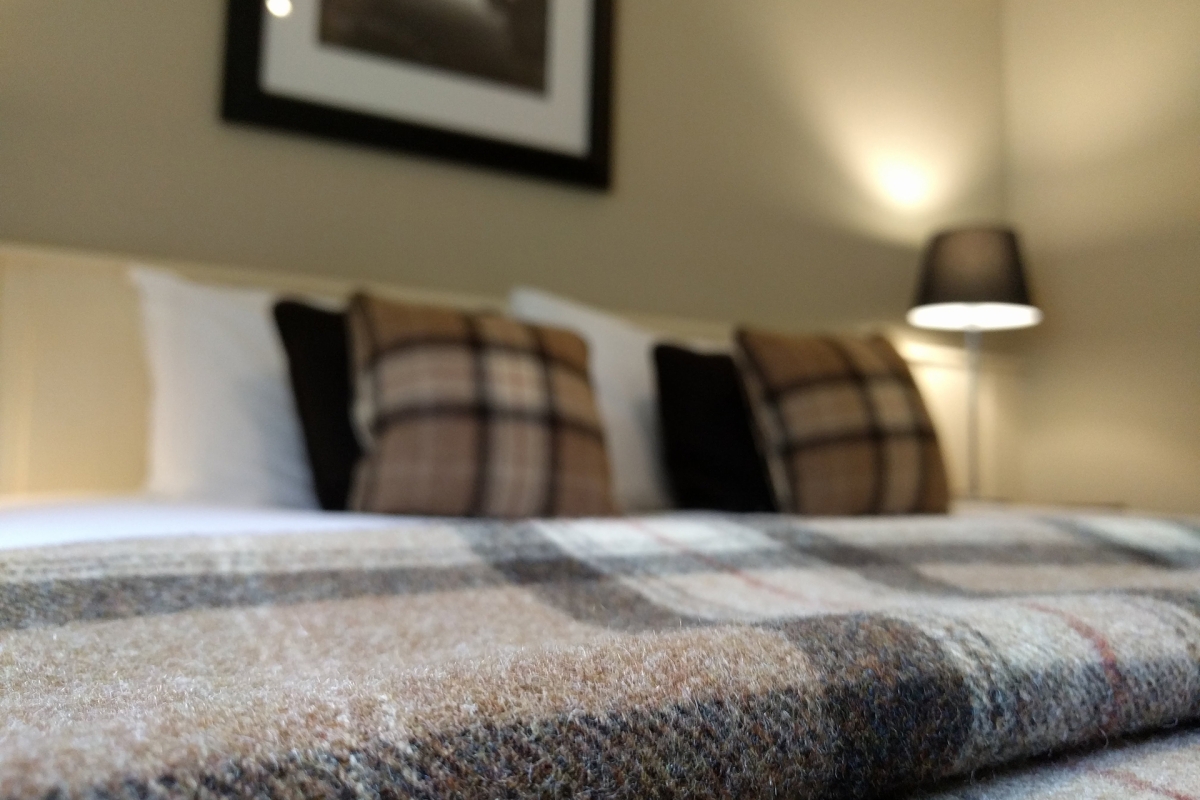 A warm wool tartan blanket on a hotel bed.