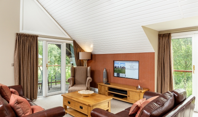 A modern seating area with tv and large windows of nature view