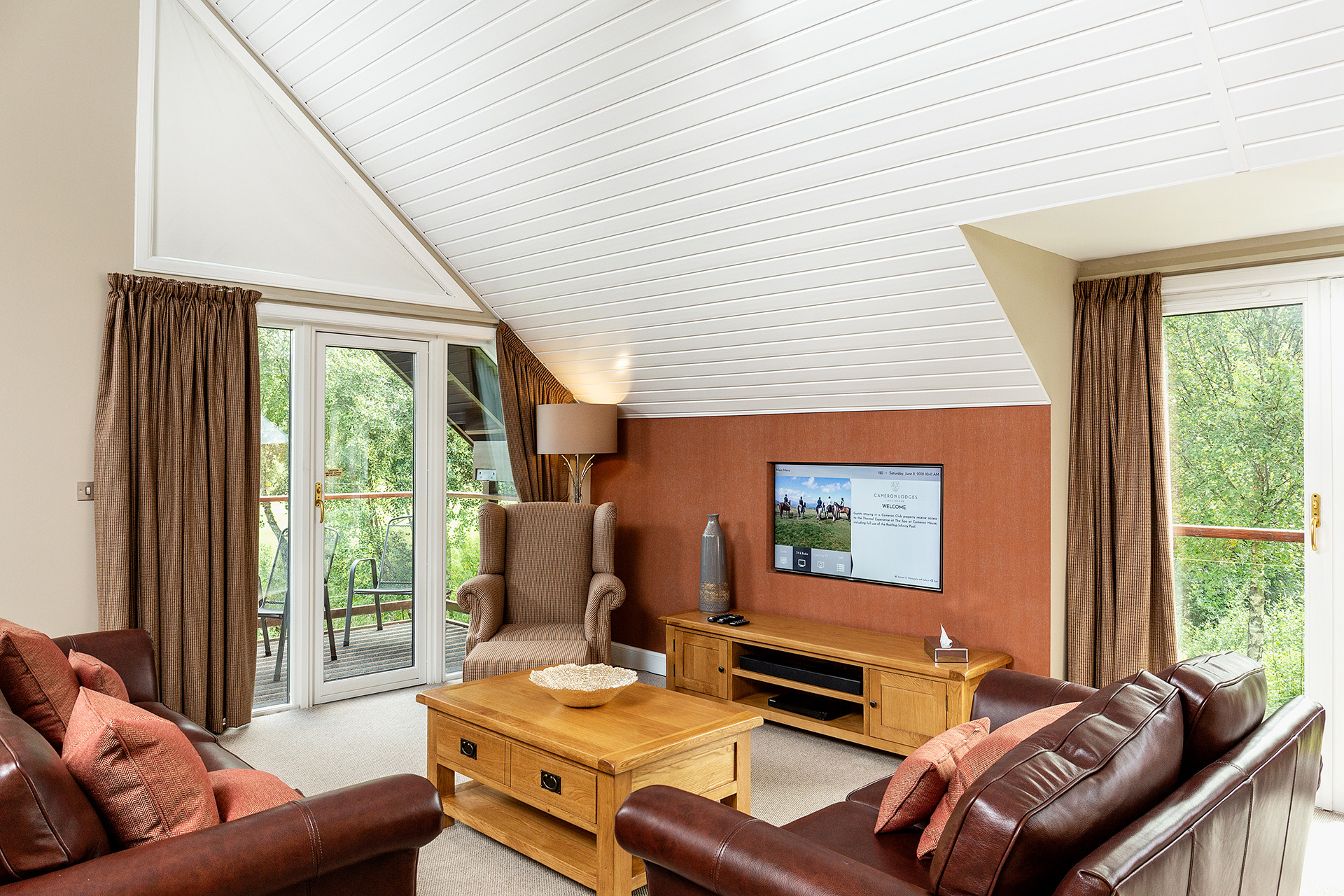 A modern seating area with tv and large windows of nature view