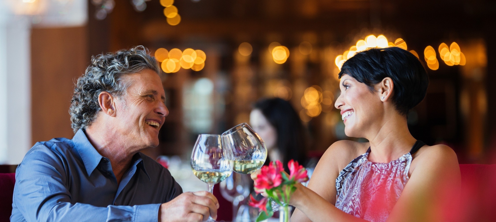 A man and woman celebrating over dinner and enjoying glasses of wine.