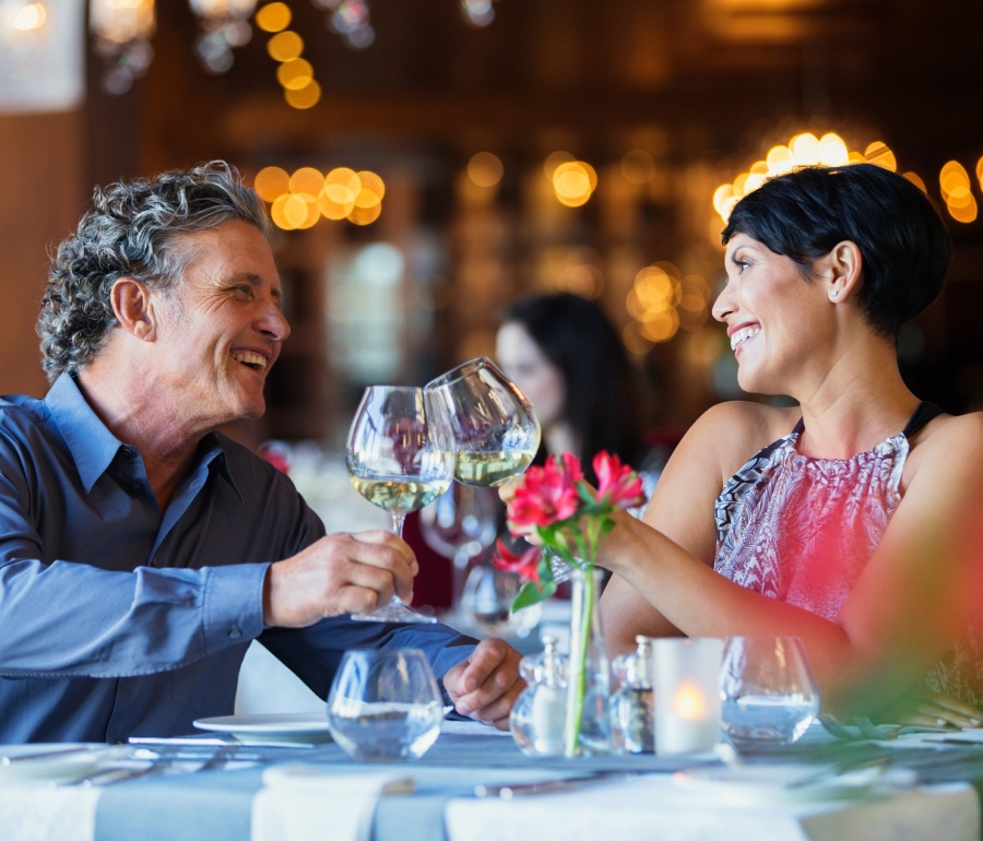 A man and woman celebrating over dinner and enjoying glasses of wine.