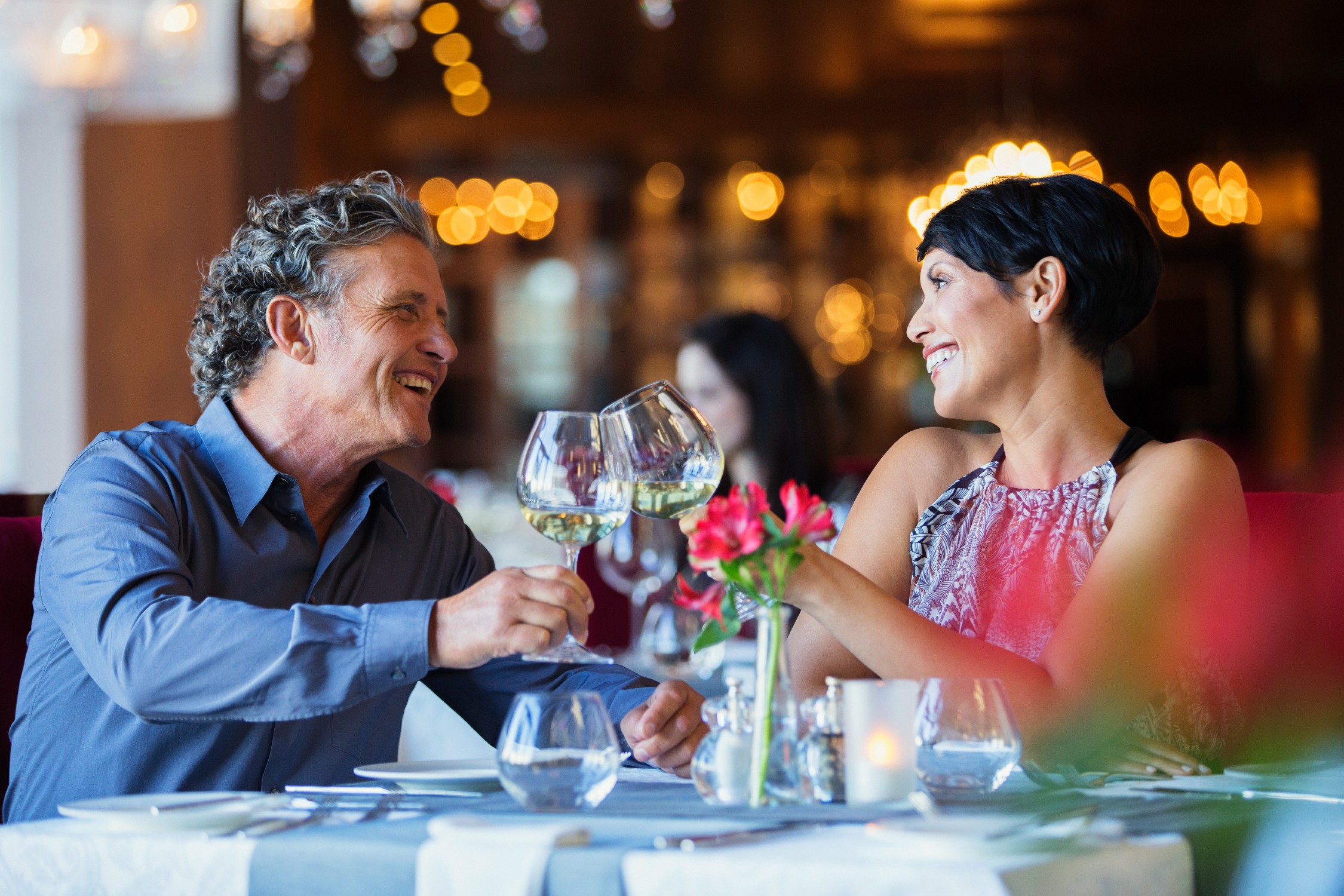 A man and woman celebrating over dinner and enjoying glasses of wine.