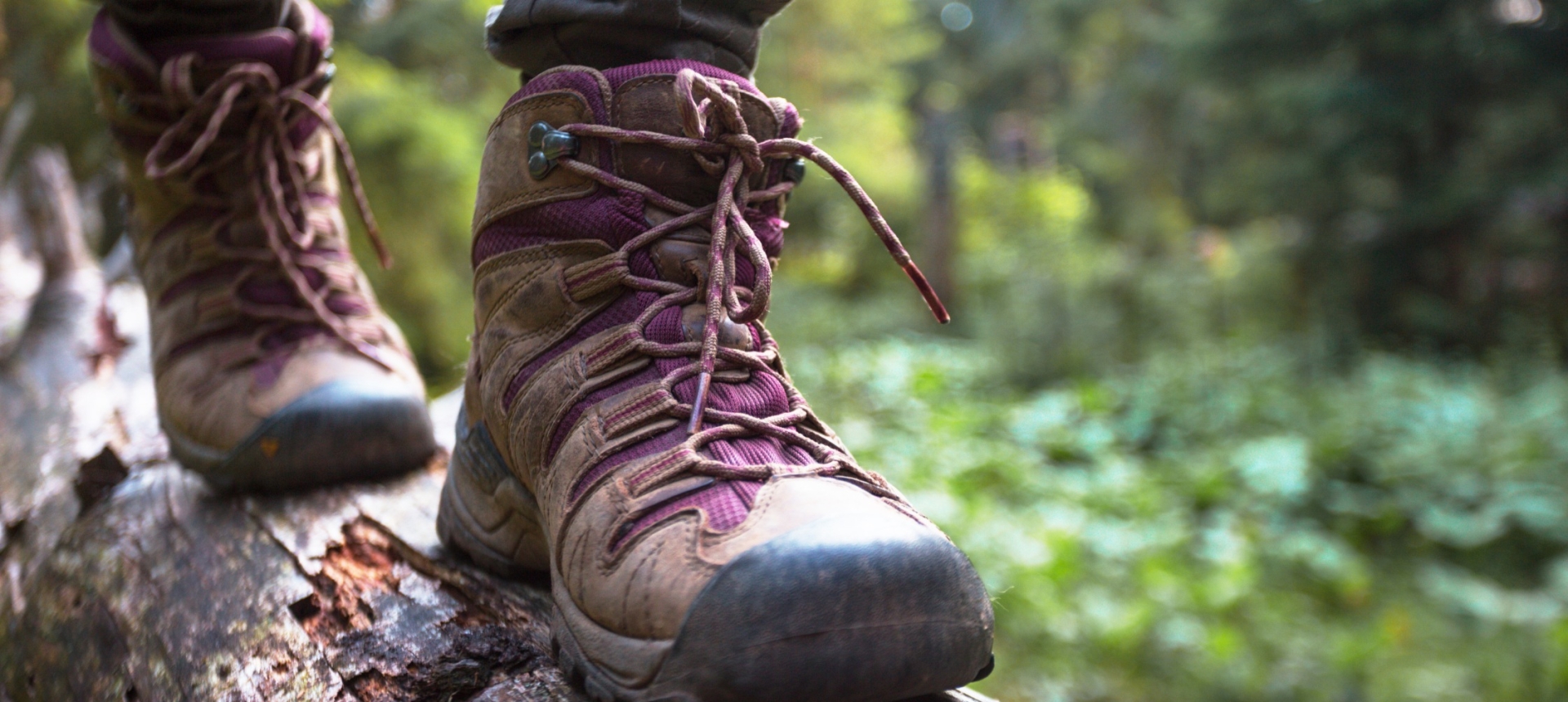 A person wearing hiking boots walking across a log