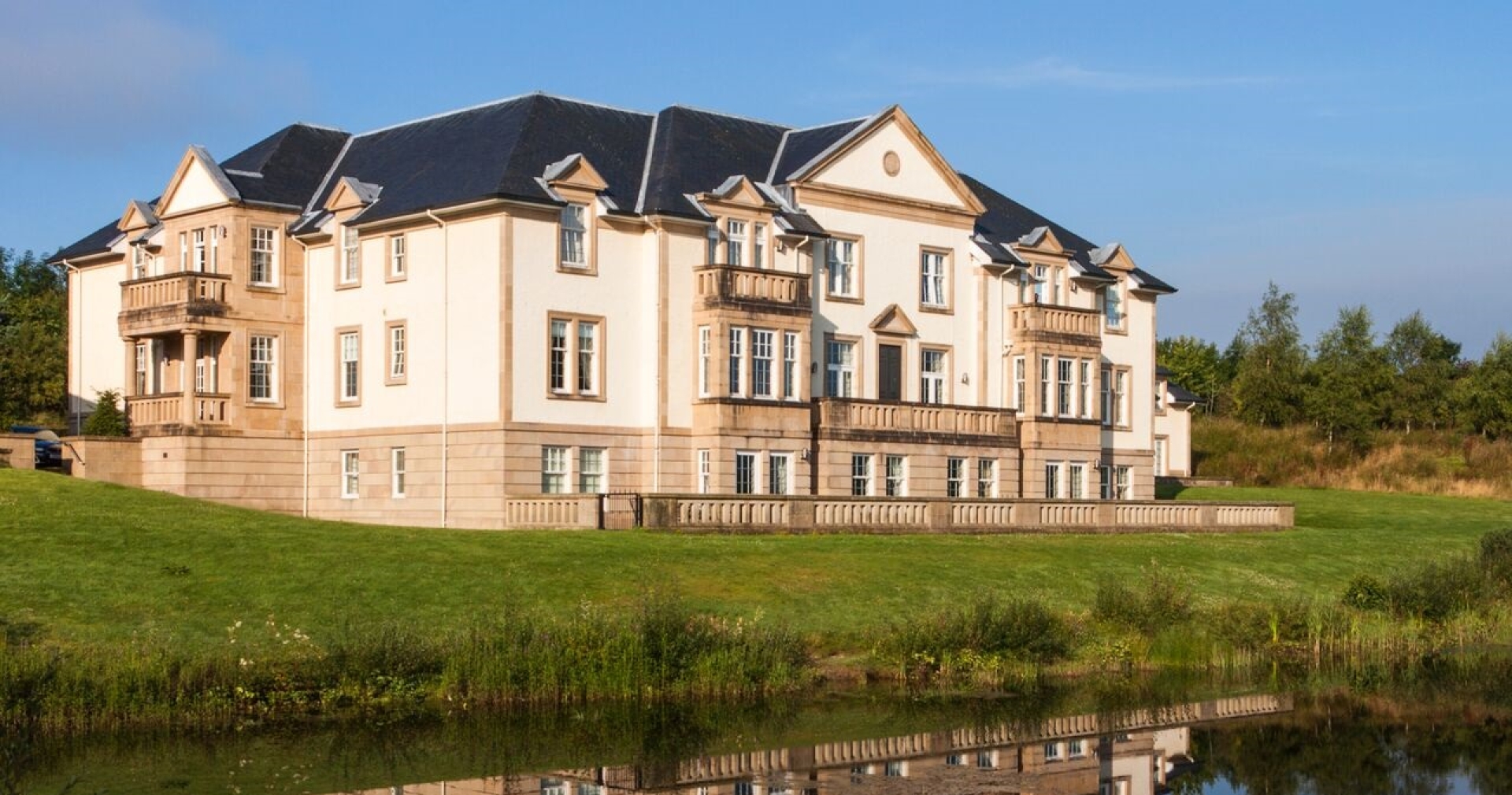 Exterior of Loch Lomond Apartments reflected in a nearby pond.