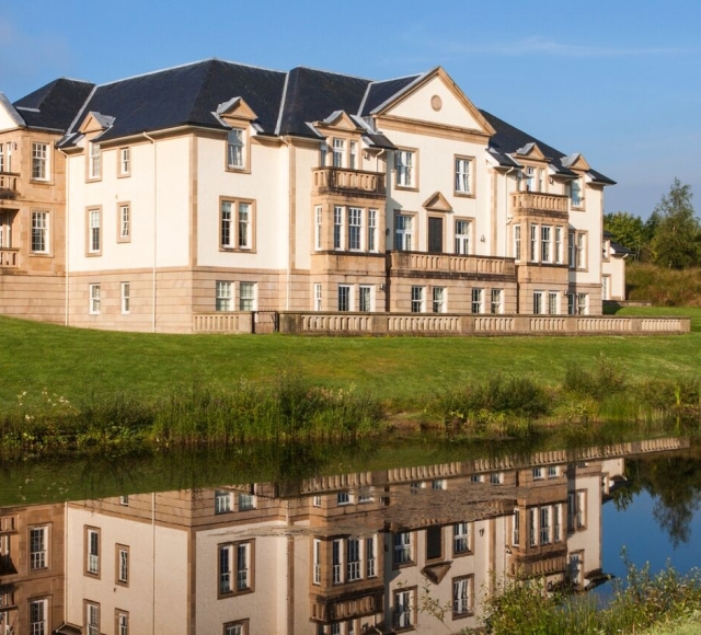 Exterior of Mansion House Suite reflected in a pond