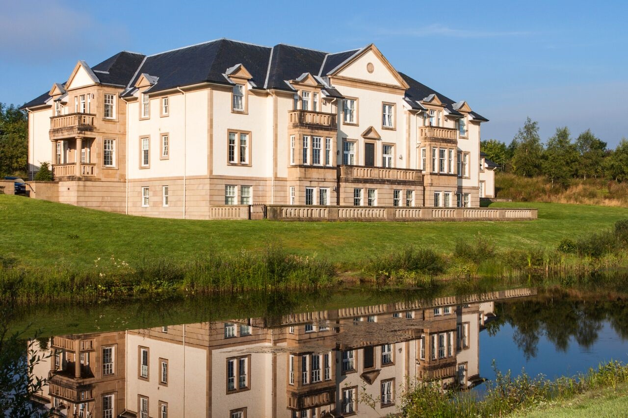 Exterior of Loch Lomond Apartments reflected in a nearby pond.