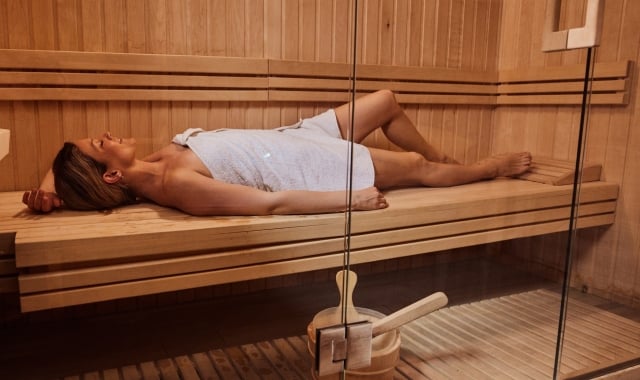 A woman lying in a towel in a sauna.