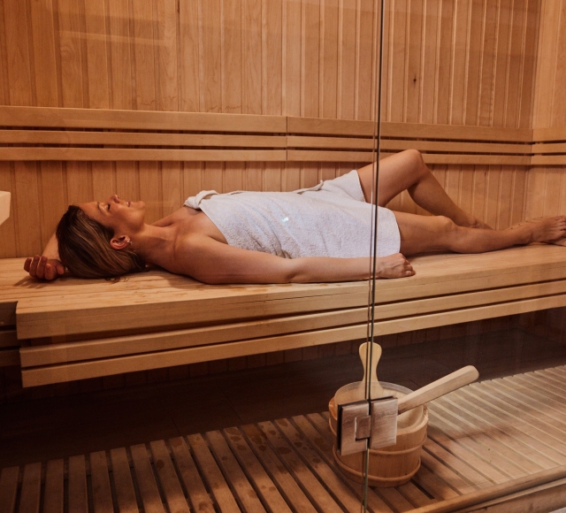 A woman lying in a towel in a sauna.