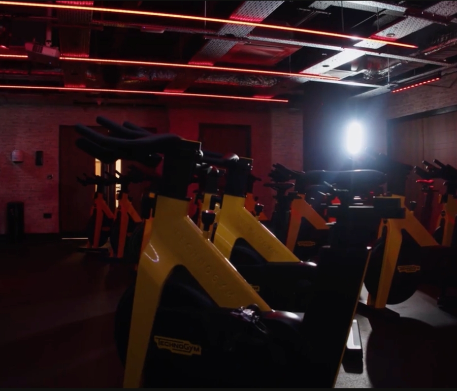 spin bikes in a darkened gym illuminated by red fluorescent lights.