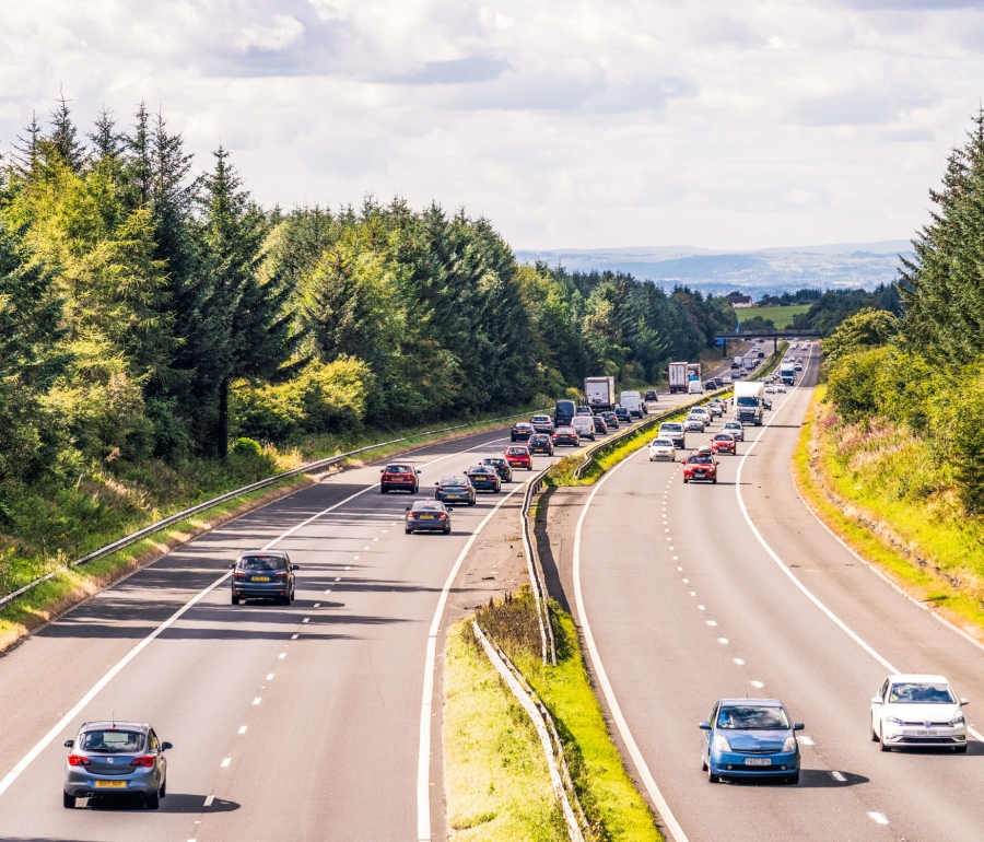 Cars driving on highway with trees and grass.