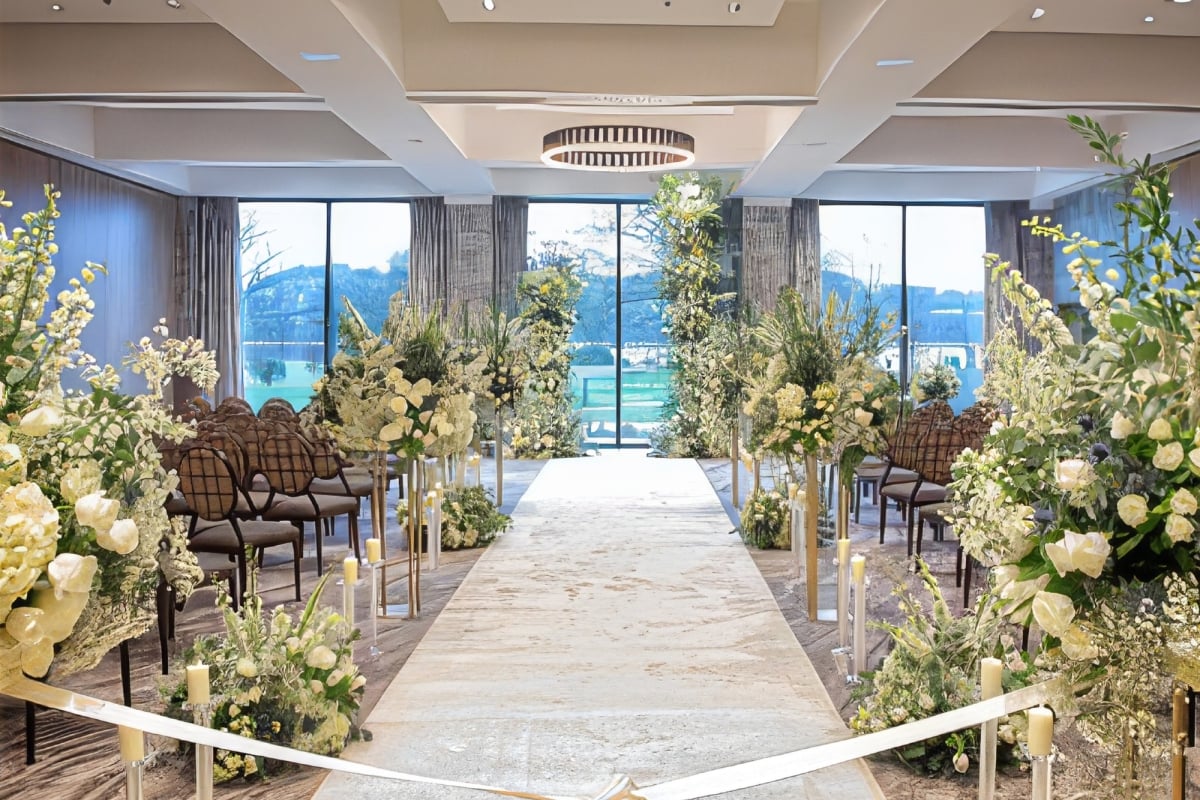 An elegant wedding ceremony aisle with white flowers lining either side of the aisle.