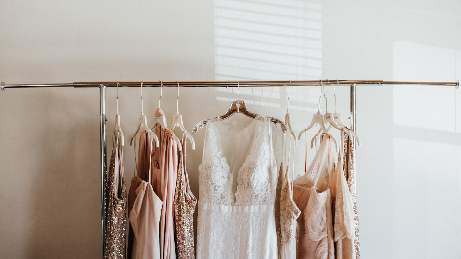 Bride and bridesmaid dresses hanging on a rack.