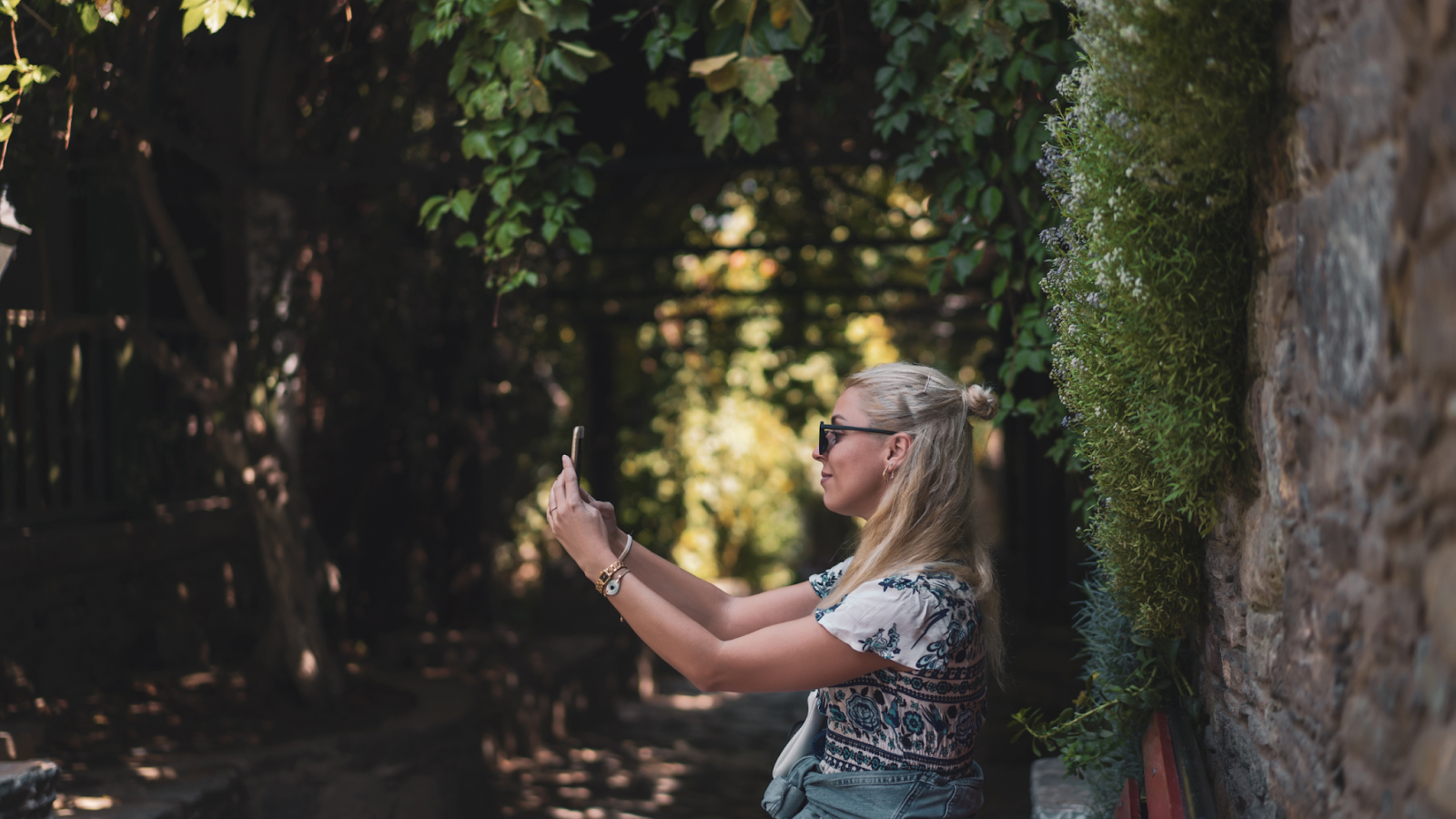 A blonde woman taking a selfie in a forest.